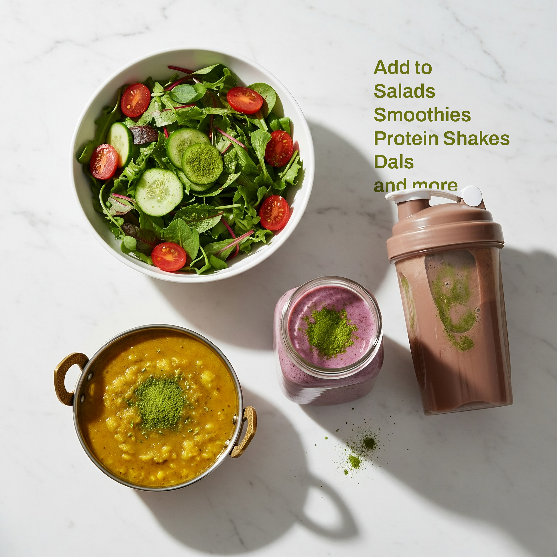 An overhead flat lay shows four food items on a white marble surface, each featuring a sprinkle of bright green sunflower microgreen powder. From top to bottom and left to right, there is: a white ceramic bowl of green salad with cherry tomatoes and cucumber, a brass katori bowl of yellow dal tadka, a clear glass mason jar with a purple-pink berry smoothie, and a brown plastic protein shaker bottle containing a chocolate protein shake. Soft natural light creates subtle shadows.